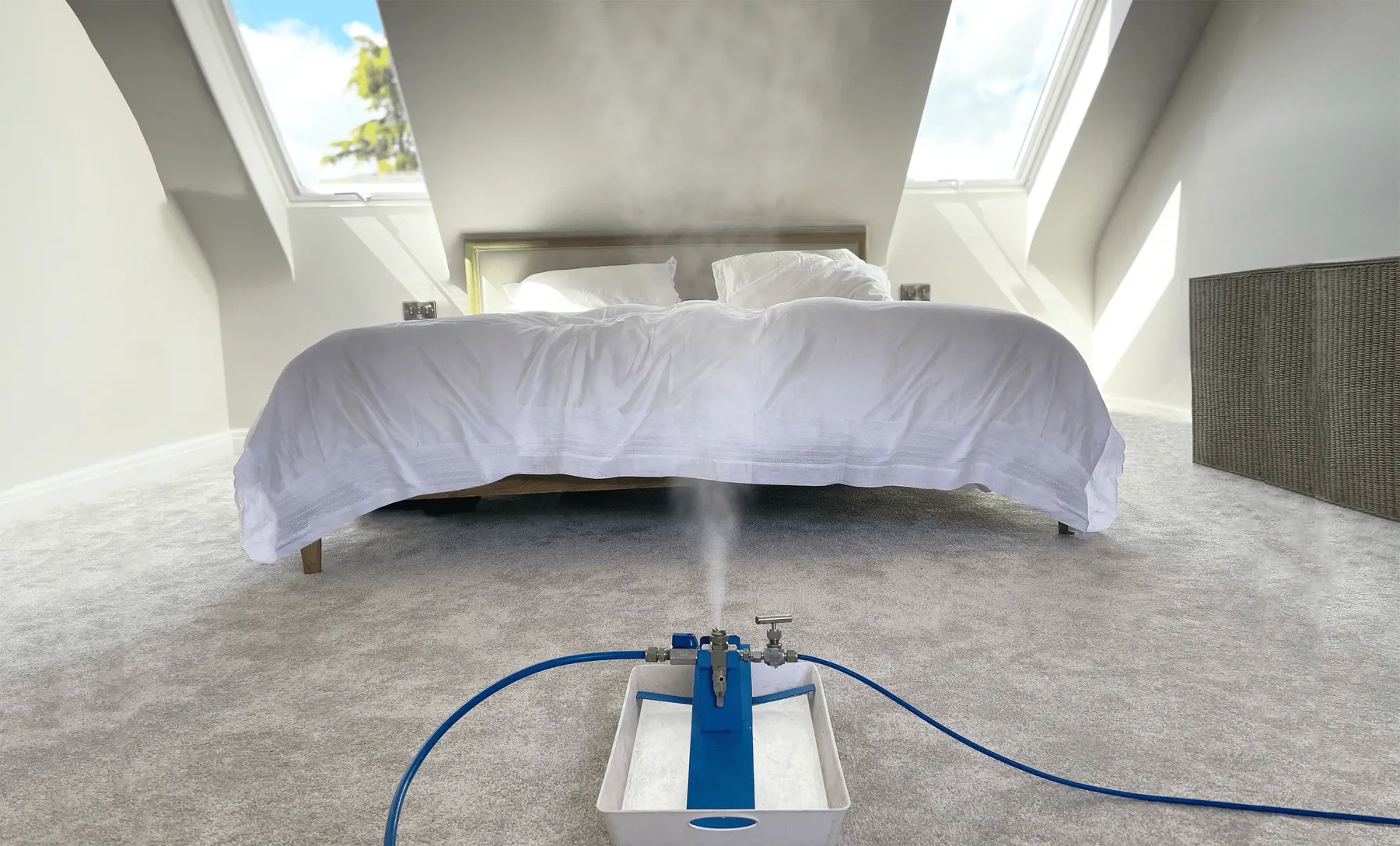 A vapor unit running at the foot of a bed in an attic bedroom