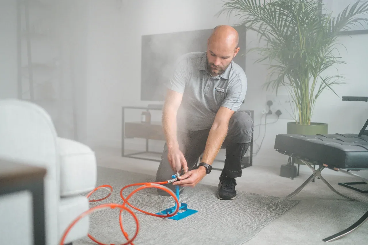A technician setting up vapor equipment in a living room