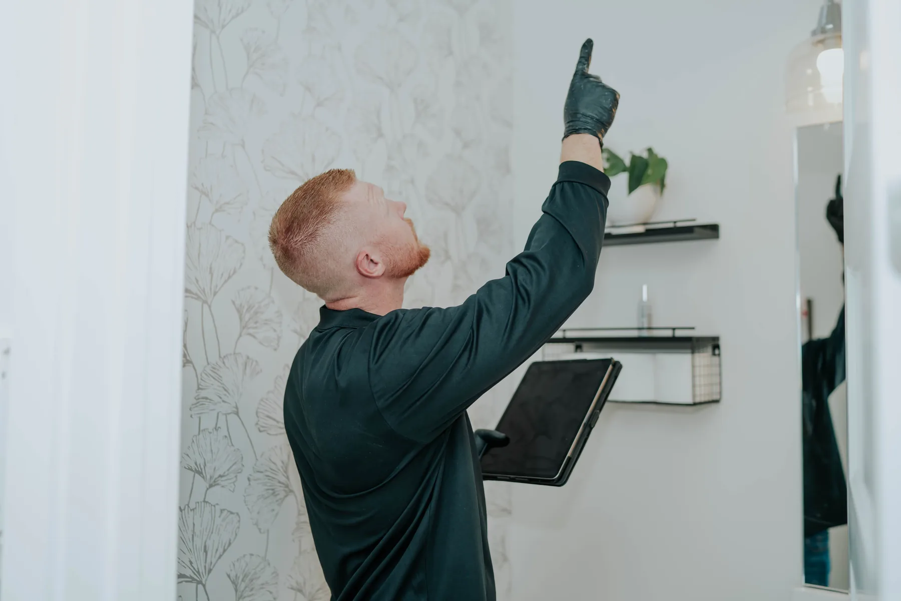A technician checking a ceiling with a tablet in hand