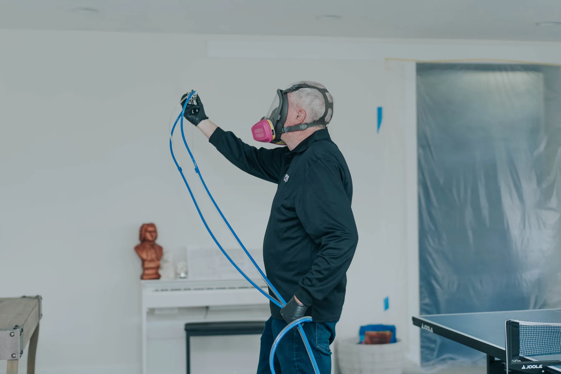 A technician in a respirator treating a wall
