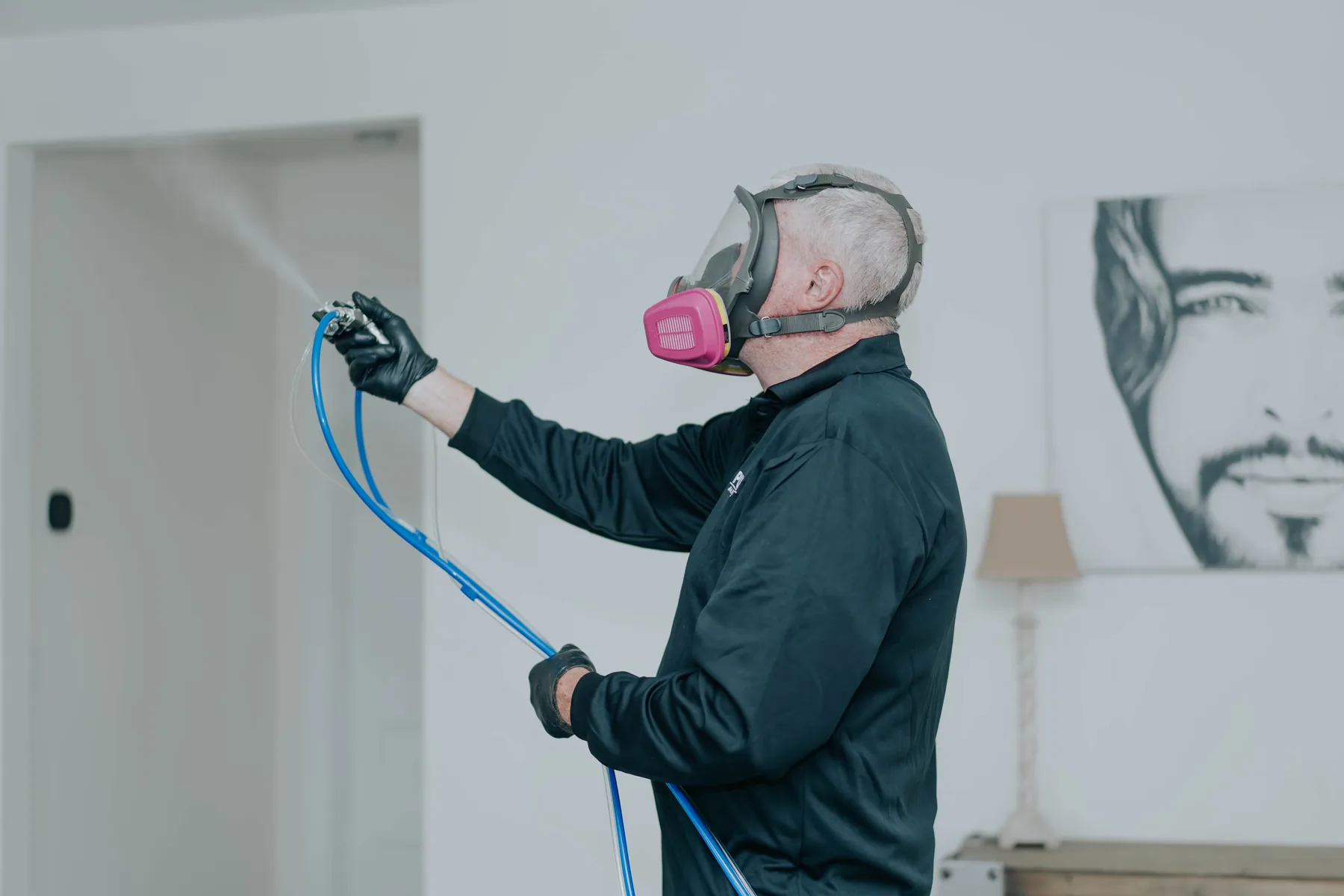 A technician in a respirator treating a wall