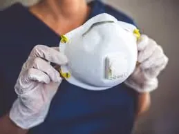 Gloved hands holding an N95 respirator